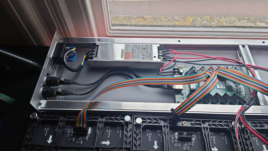 The internals of an LED panel on a workbench by a window 
