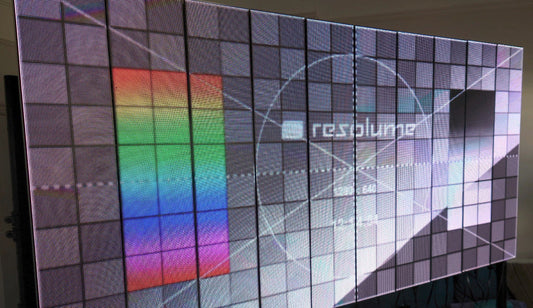 Large digital LED display with geometric test card patterns and a rainbow color block.