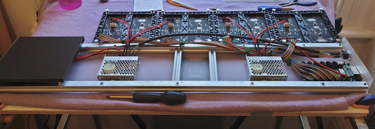 Internal view of an LED panel with power supplies, wiring, and circuit board showing.
