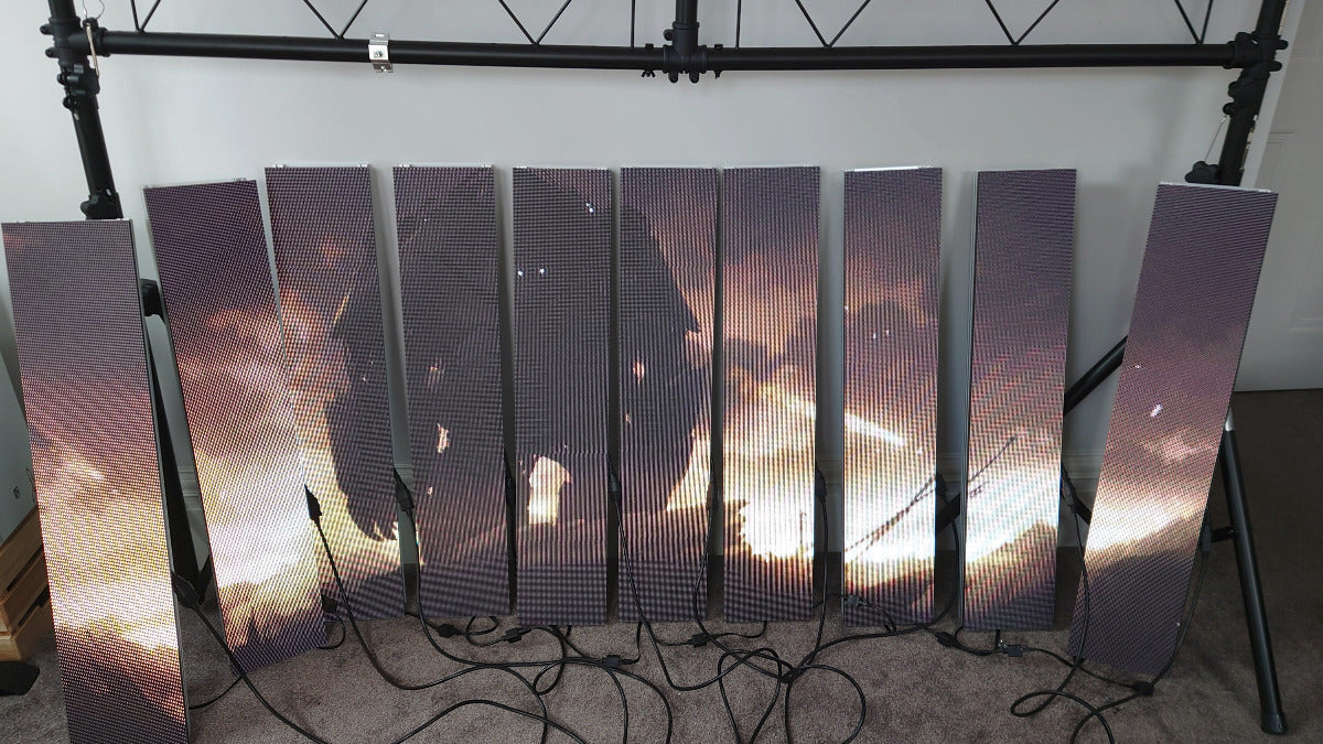 Row of LED panels displaying a glowing image leaning against a wall and lighting rigging