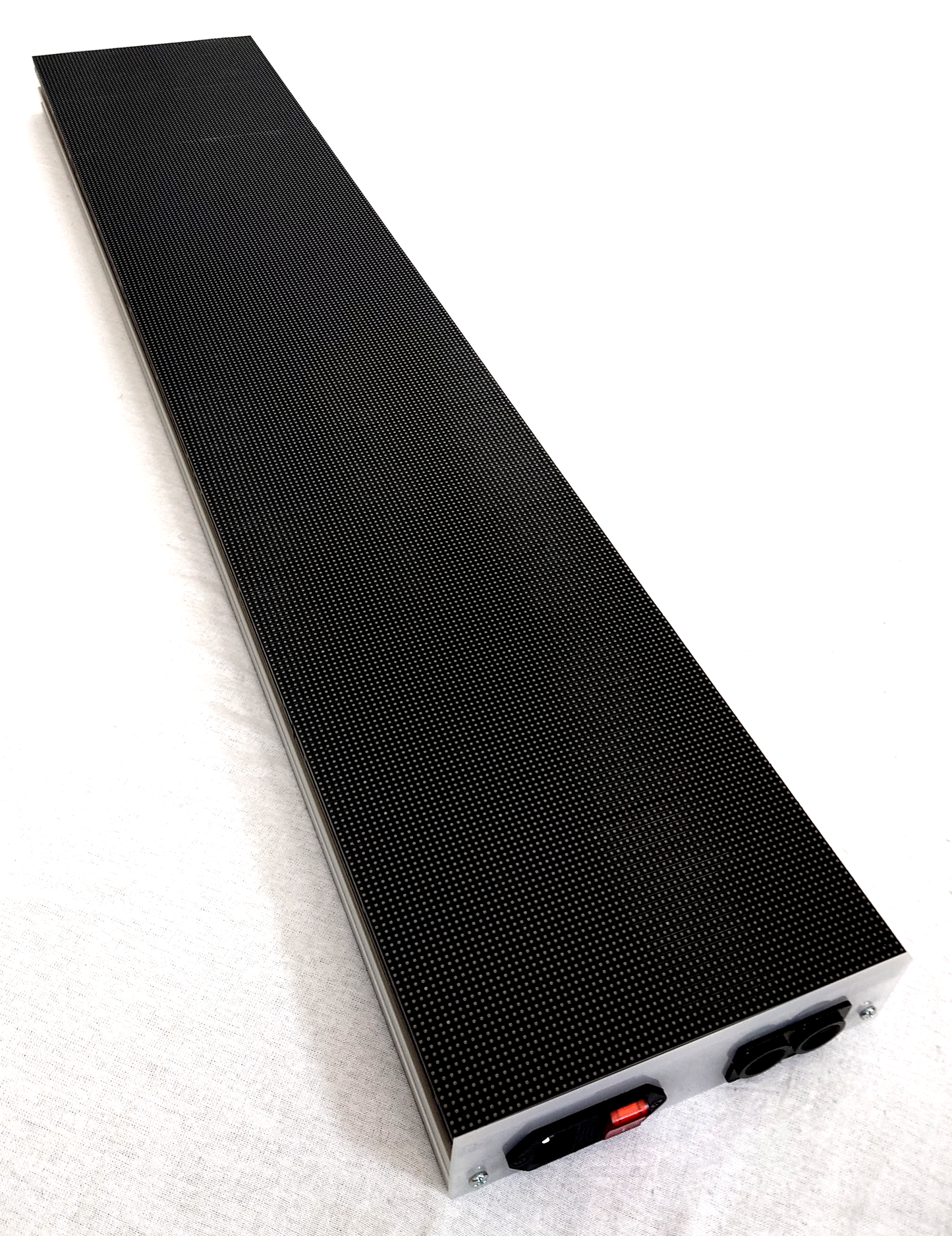 A long, narrow black rectangular LED panel with a textured surface and a silver metal end cap, photographed on a white background. The end cap shows a red switch and two black connectors.