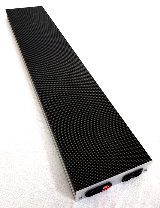 A long, narrow black rectangular LED panel with a textured surface and a silver metal end cap, photographed on a white background. The end cap shows a red switch and two black connectors.