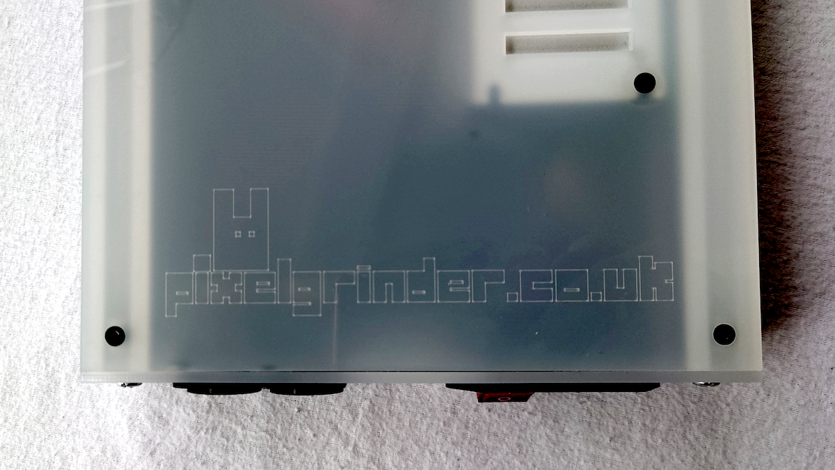 A translucent frosted white plastic enclosure or case with pre-drilled screw holes with a faint 'pixelGrinder.co.uk' URL and stylised bunny logo etched into the surface