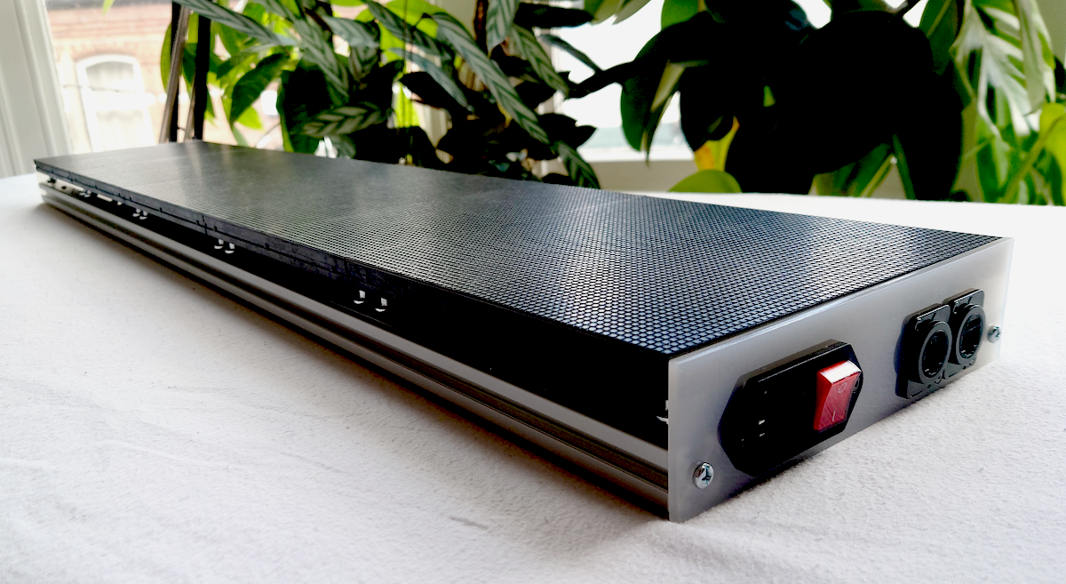 An LED panel showing the base board with a power port and 2 network ports panel mounted onto the white opaque acrylic on a white surface