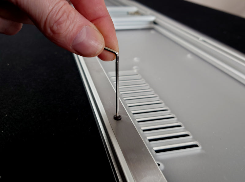 Once  aligned, secure the metal strip to the  frame by tightening the screws